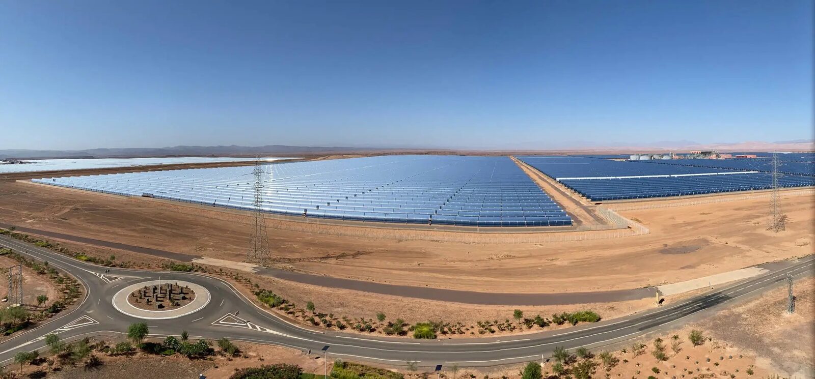 A concentrated solar power plant with rows of parabolic trough mirrors in a desert.