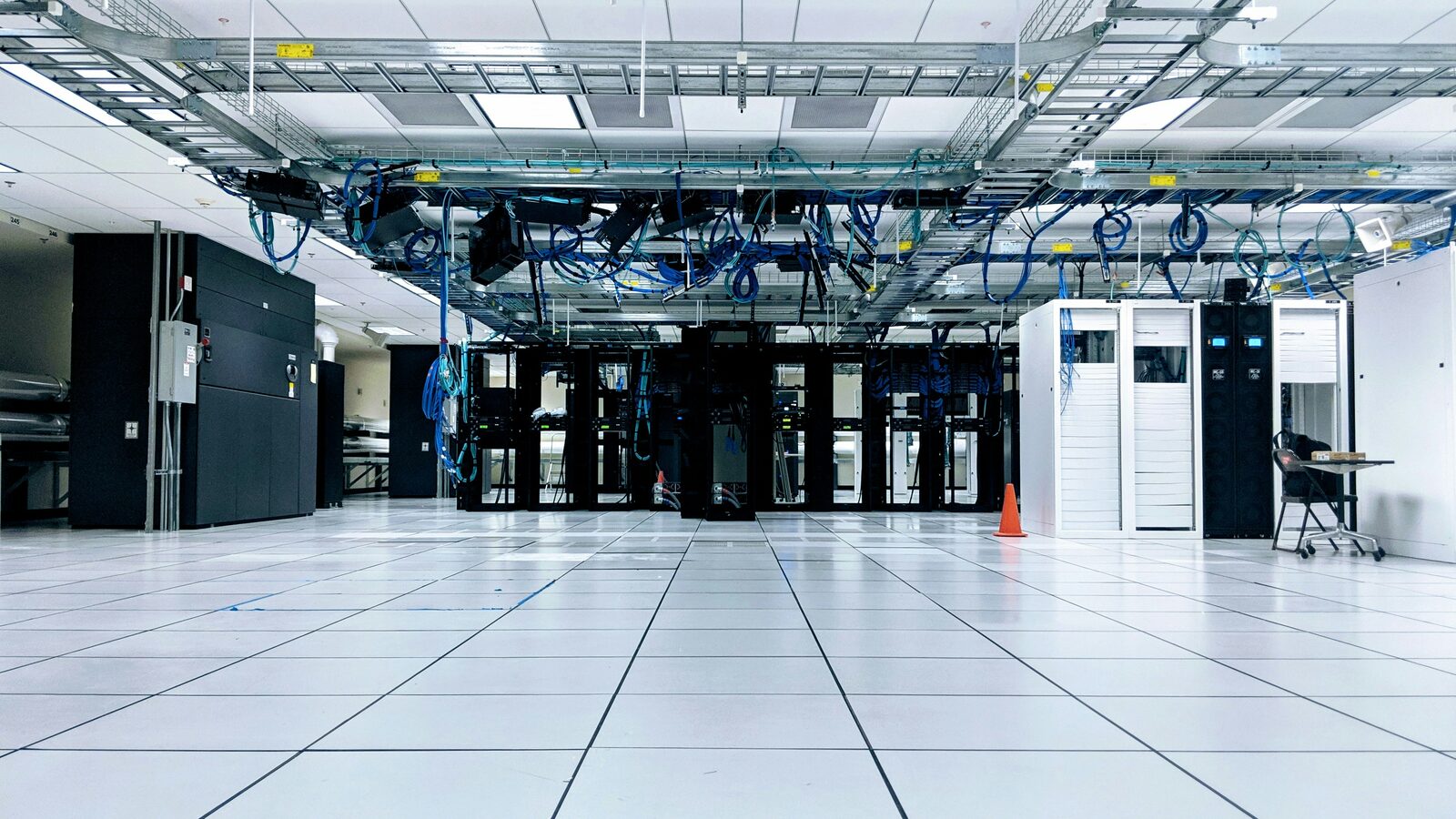 A data centre server hall with rows of racks and overhead cabling above a raised floor.